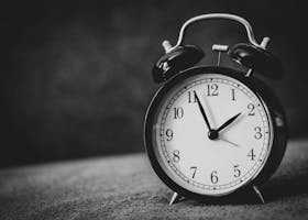 Monochrome close-up of a classic alarm clock displaying ten o'clock.